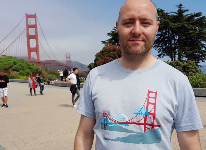 A man standing in front of the Golden Gate bridge, wearing a t-shirt with a print of the Golden Gate bridge.